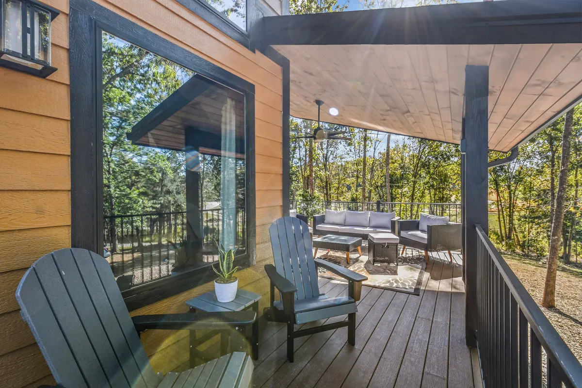 A pair of Adirondack chairs are positioned on an outdoor seating area, facing lush greenery. The space invites couples to relax, sip coffee, or share a quiet moment while immersed in the peaceful forest setting.